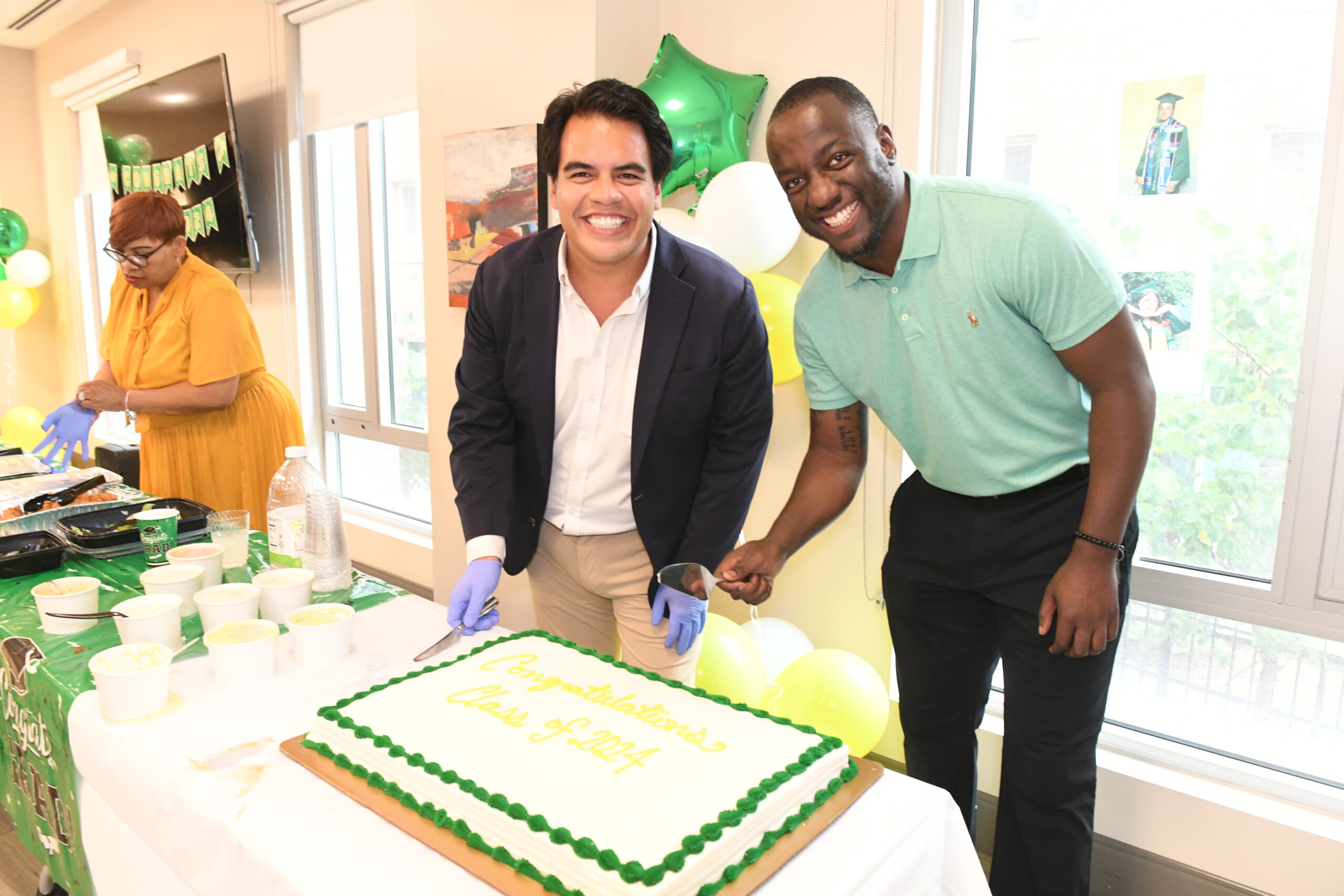 Two men smiling, ready to cut a cake