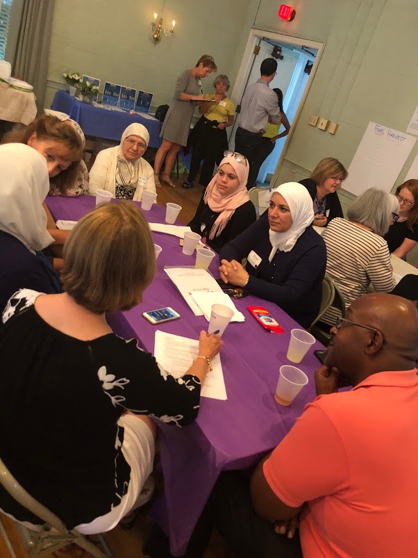 Women in headscarves discussing around a table at a community event