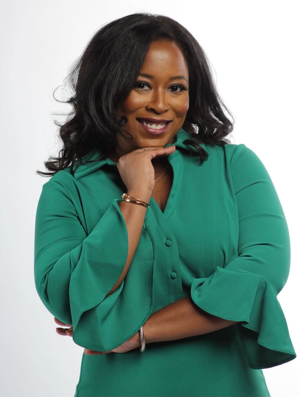 Woman posing and smiling for the photo, dressed in a green blouse.