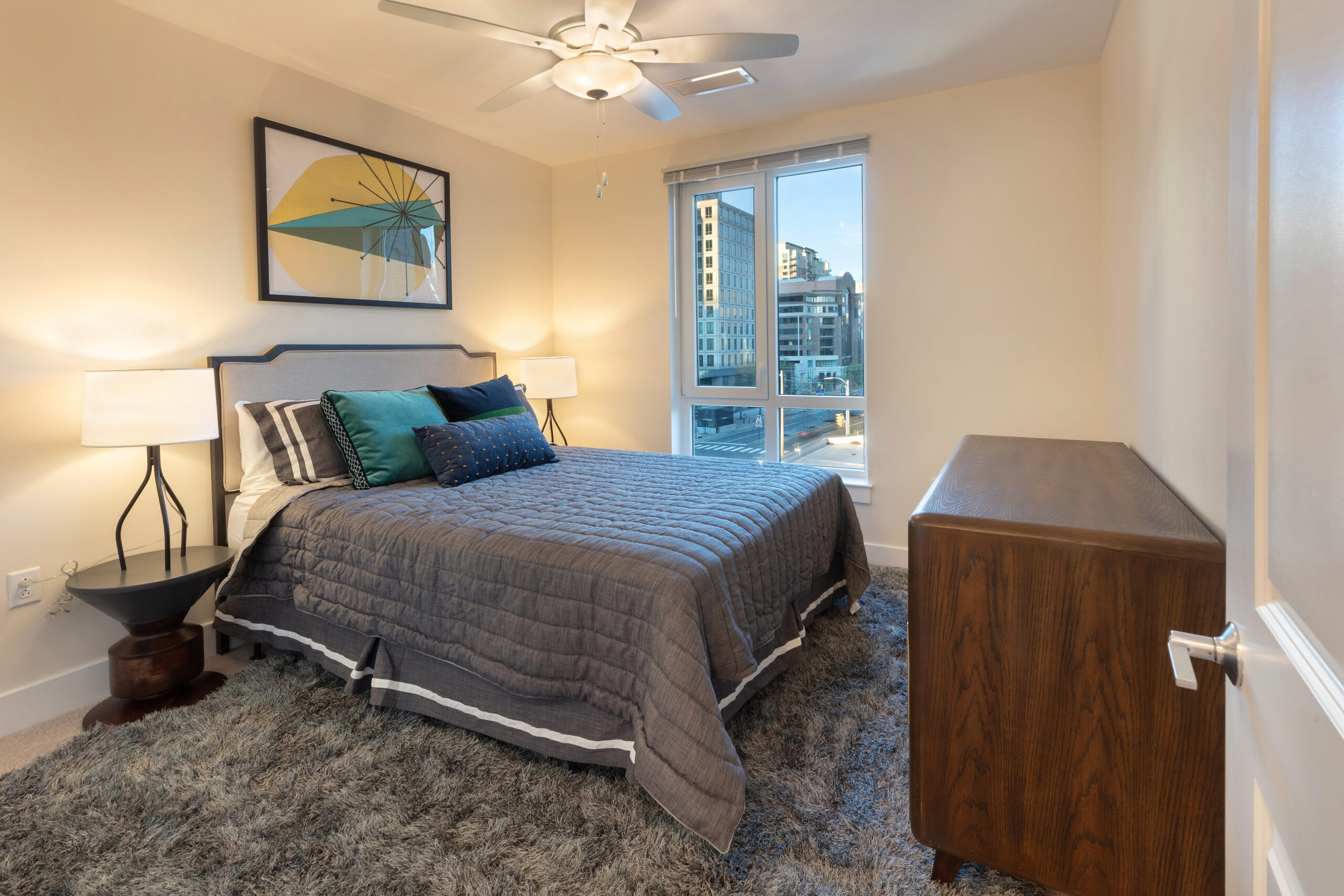 Bedroom with white walls, gray blanket on the bed, gray rug