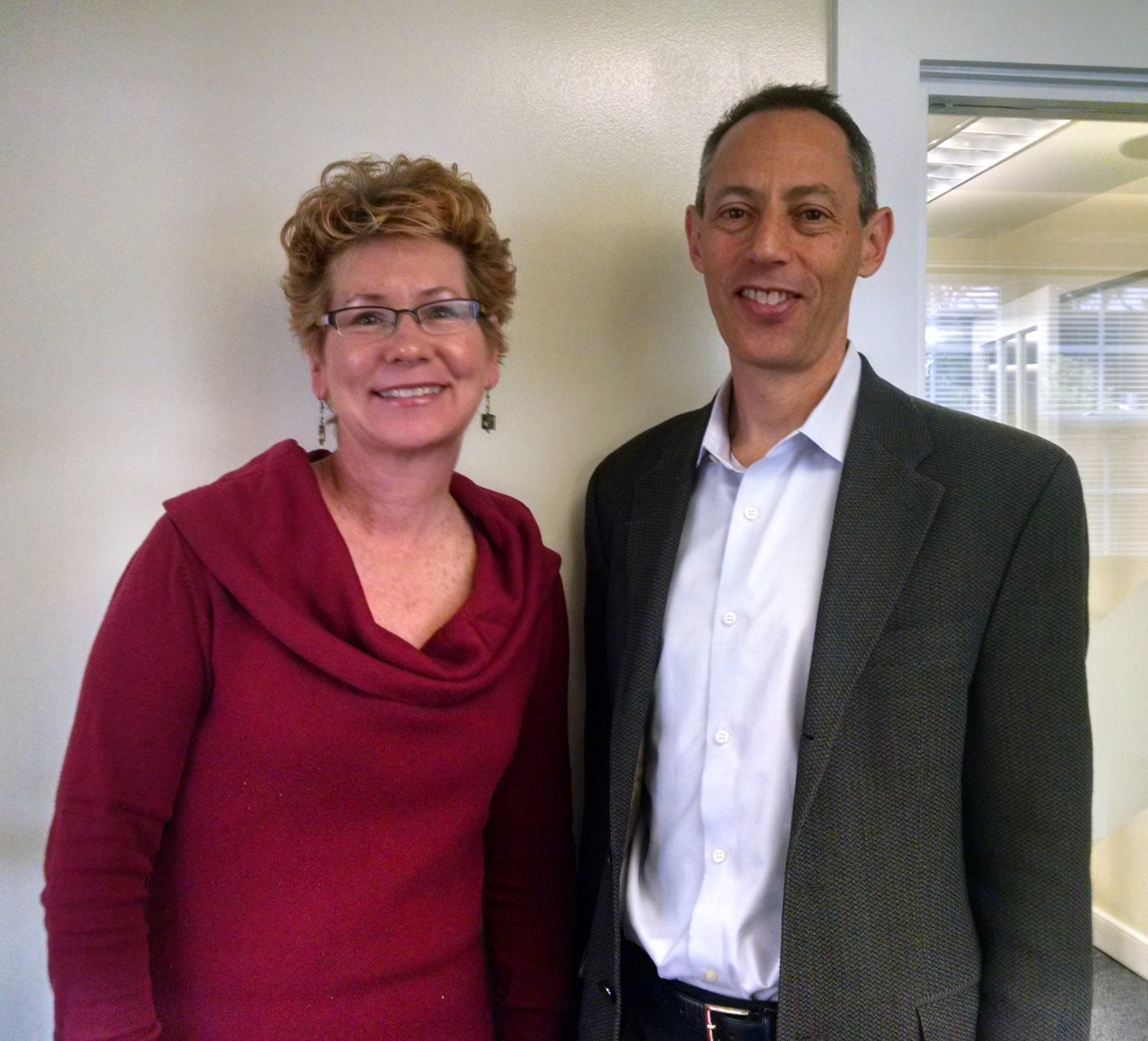 Smiling woman and man posing indoors in formal attire.