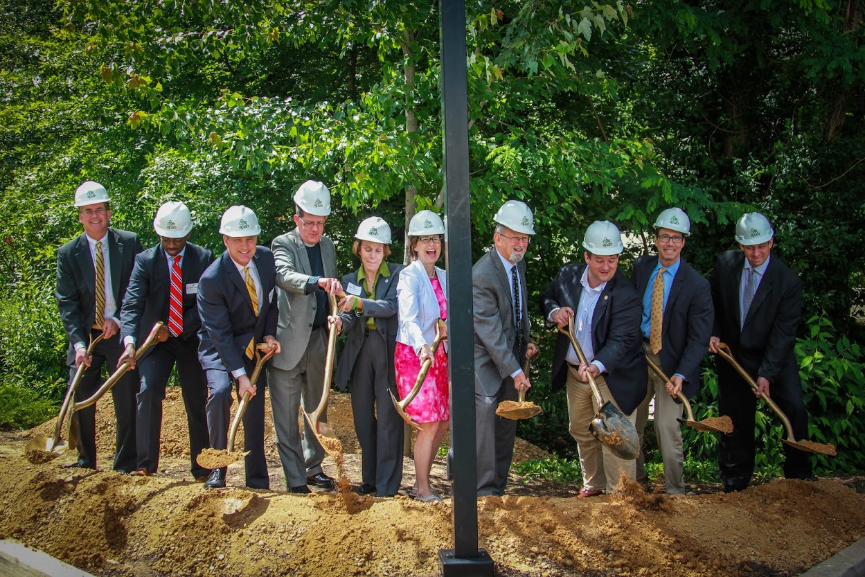 Group photo of officials and community leaders celebrating a housing project milestone.