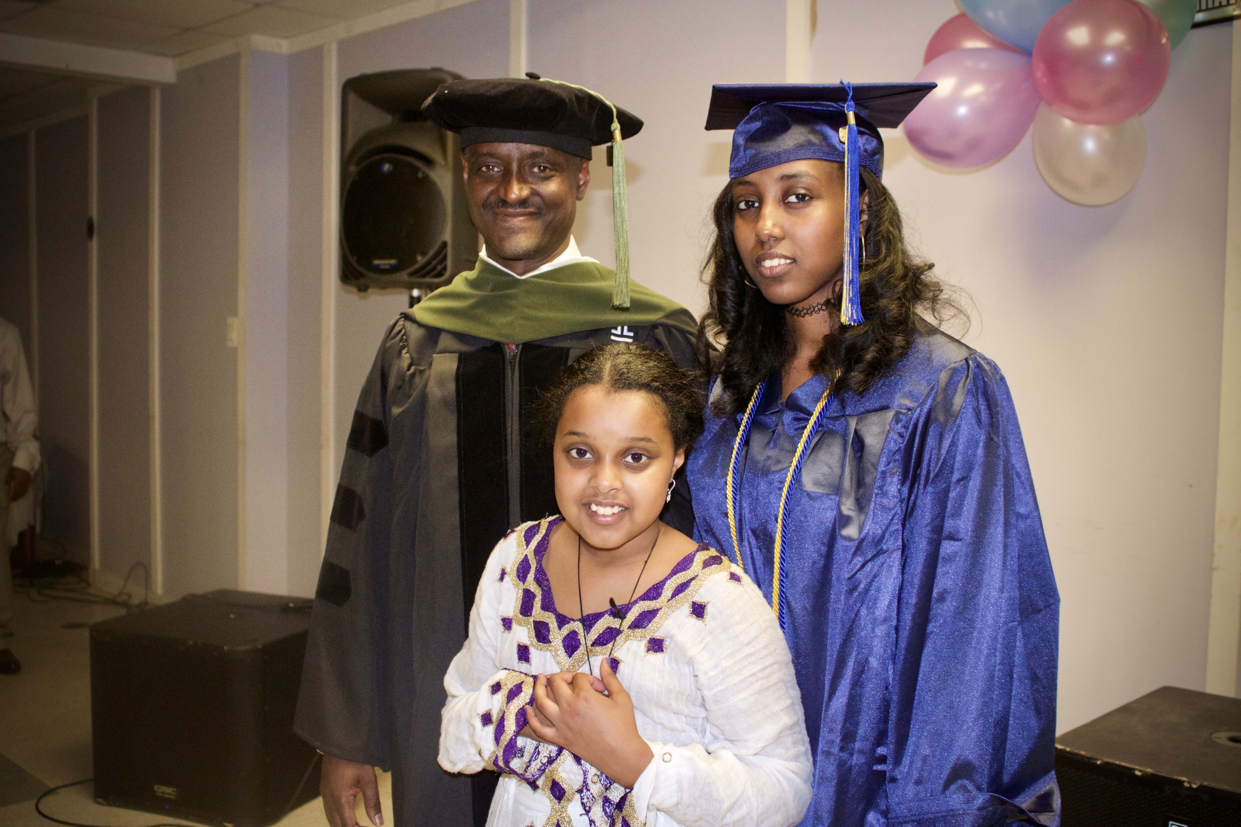 Graduate posing with two family members at a graduation ceremony.