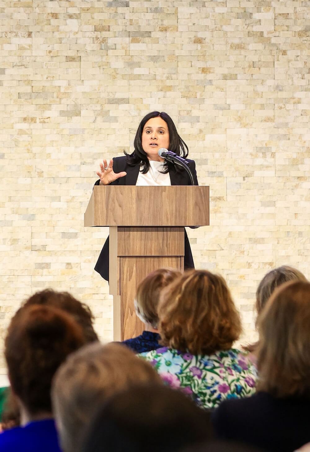 A woman speaks at a podium in front of an audience.