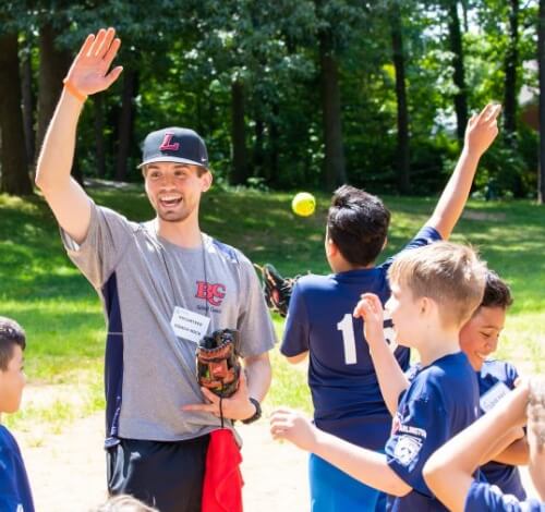 Coach leading kids in a baseball practice outdoors