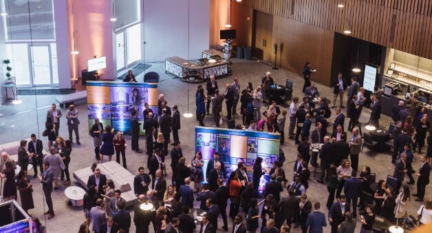 networking event with many attendees in a modern, open venue, featuring various display booths.