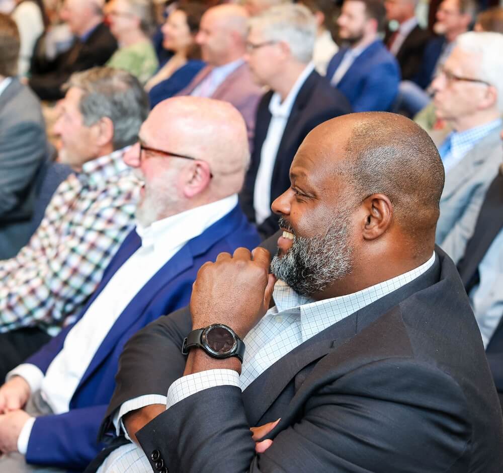 Audience members smiling and engaged during a presentation