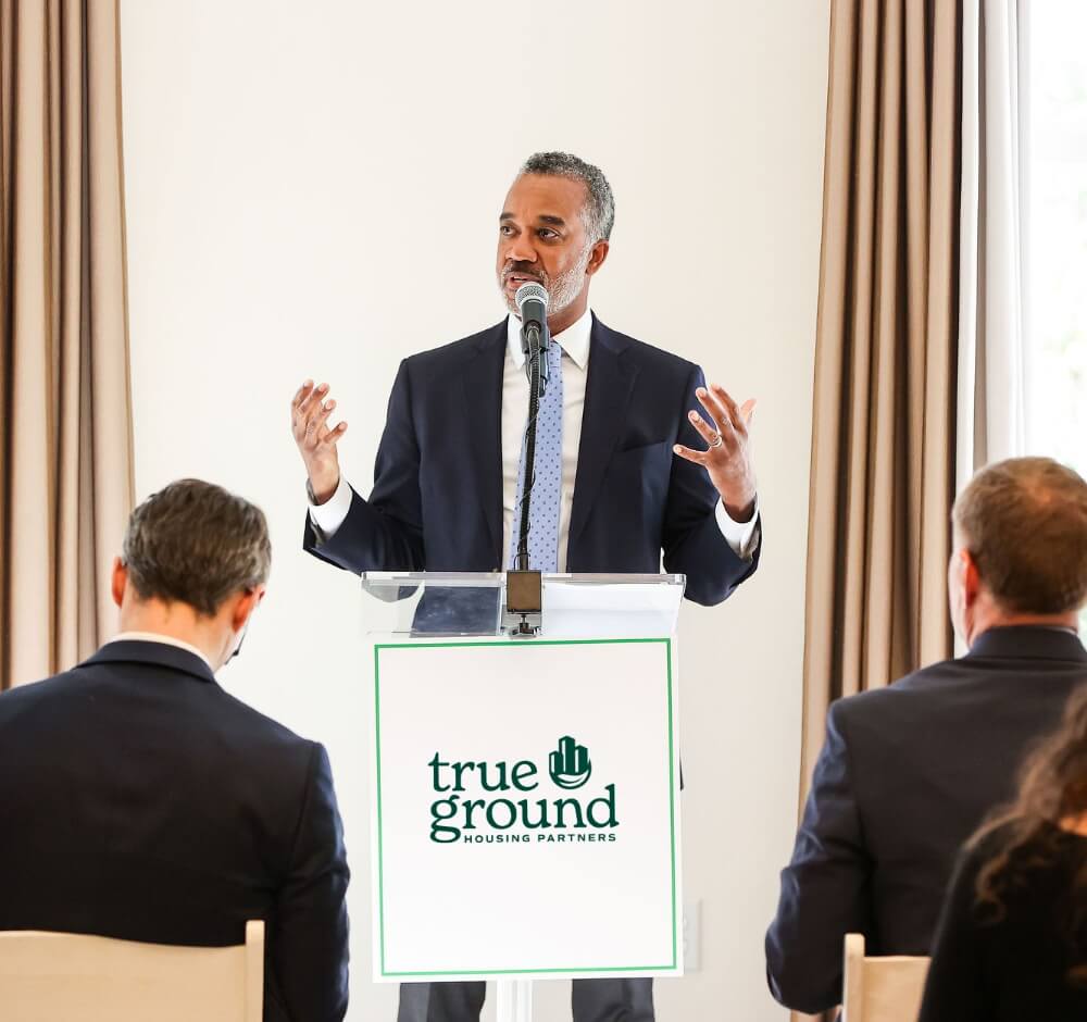 Man giving a speech at a True Ground Housing Partners event