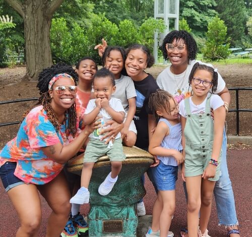 Group of smiling children and adults posing outdoors.