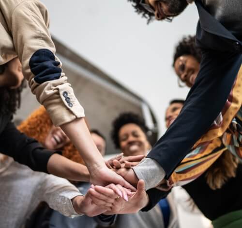 Diverse group of people in a circle, hands joined in unity