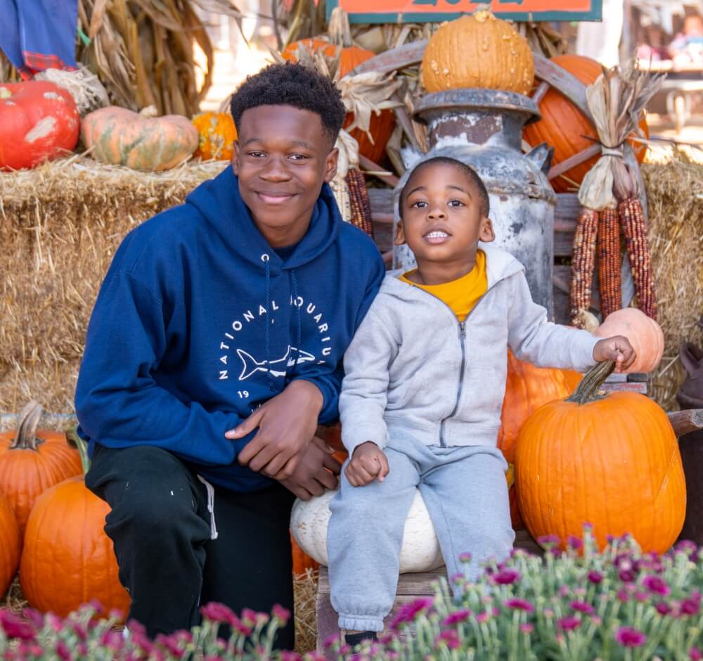 Two boys sitting with pumpkins and autumn decorations