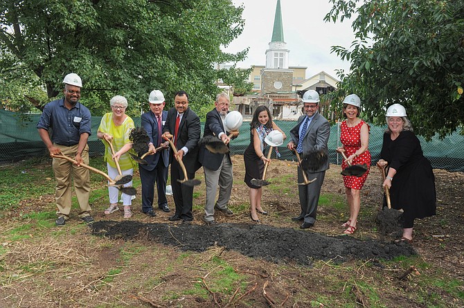 Group of people in hard hats breaking ground at Gilliam Place groundbreaking ceremony.