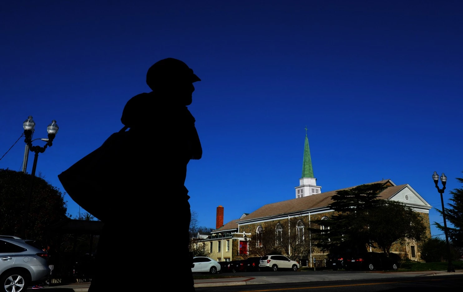 Silhouette of a person with a church steeple in the background against a clear blue sky