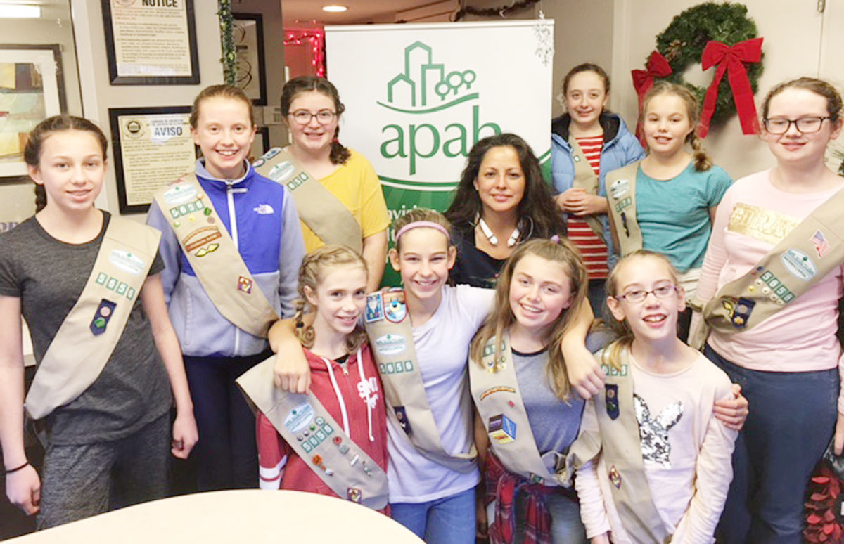 Girl Scouts in uniforms posing for a group photo at a community event.